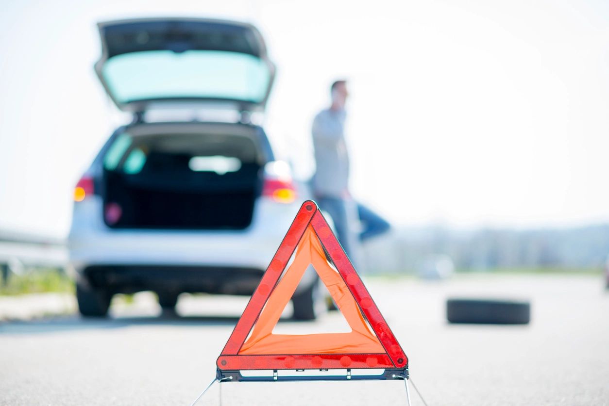 A man standing next to his car with the trunk open.