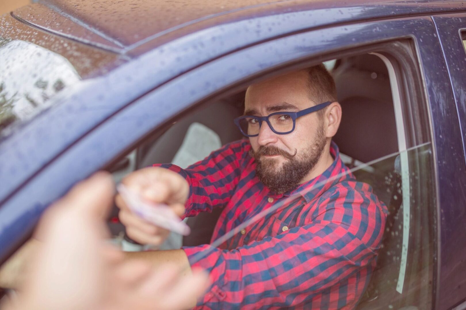 A man in glasses is driving his car